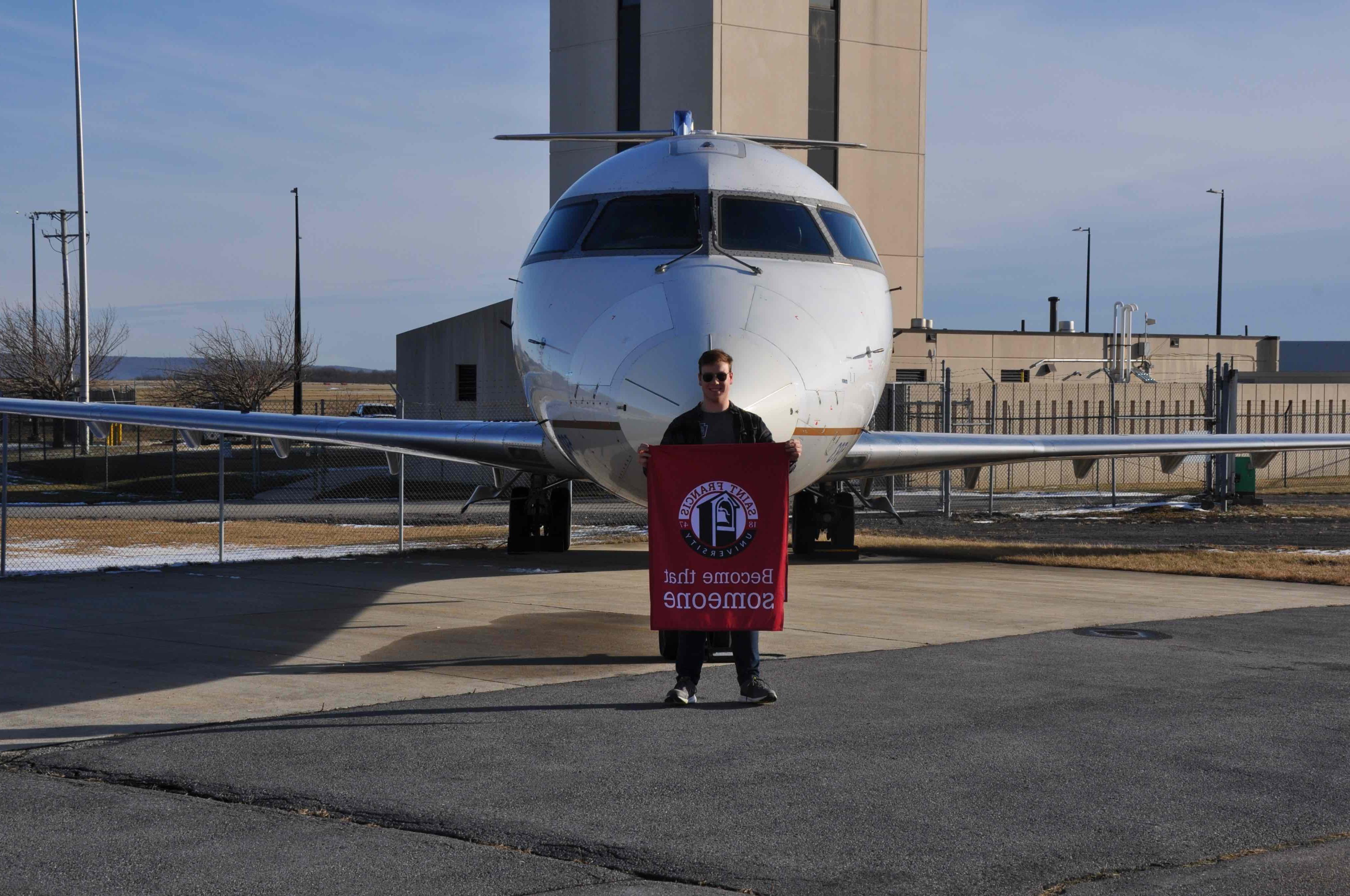 欧宝体育app入口的学生休·弗拉纳根站在西空航空公司捐赠给SFU的CRJ200机身前，该机身将被用作未来航空技术员计划的一部分 